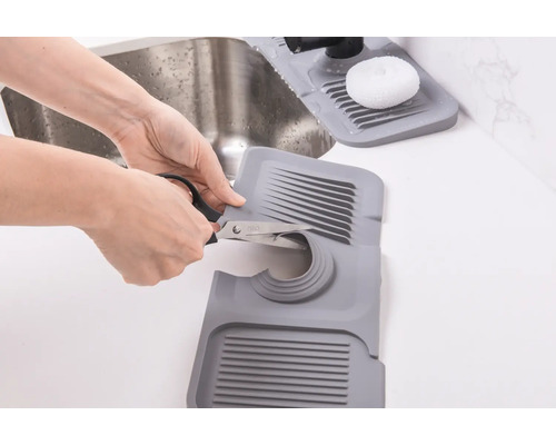 Op maat te snijden spoelbakmat van kunststof wordt met een schaar aangepast.