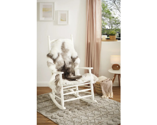 Scene met witte schommelstoel, imitatievacht, vloerkleed met patroon, bijzettafel en decoratie