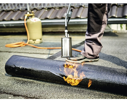 Dakdekker last bitumen dakbedekking met een brander en gasfles.