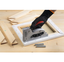 Hand met handschoen gebruikt een handtacker op een canvas