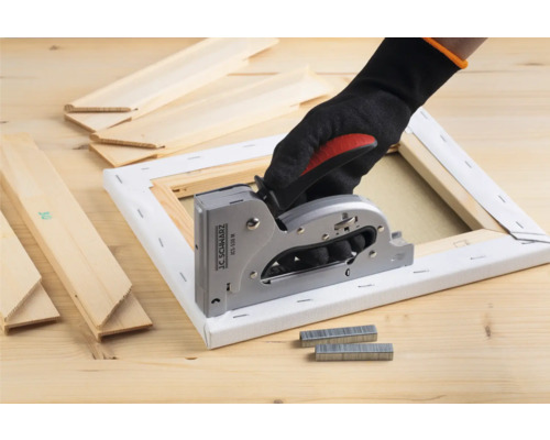 Hand met handschoen gebruikt een handtacker op een canvas