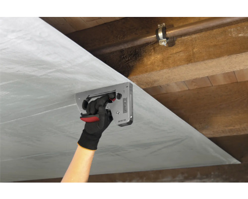 Persoon bevestigt dampremmende folie met een tacker aan een houten plafond.