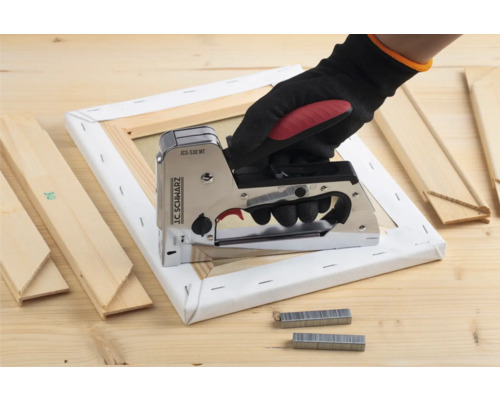 Hand met tacker op spieraam