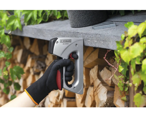 Een hand gebruikt een J.C. SCHWARZ tacker om nietjes te bevestigen.