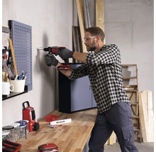 Man boort met een accuschroefboormachine in een muur in een werkplaats