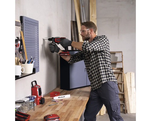 Man boort met een accuschroefboormachine in een muur in een werkplaats