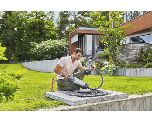 Man gebruikt een Gardena regentonpomp in de tuin voor tuinirrigatie.