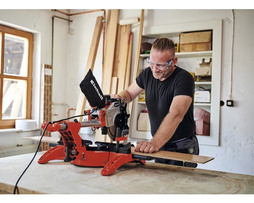 Man met veiligheidsbril werkt met een Einhell afkort- en verstekzaag in een werkplaats.