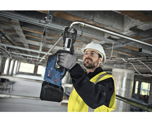 Een vakman gebruikt een accu perstang van Bosch om een metalen buis te persen.