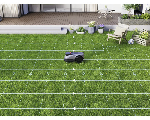 Een robotmaaier maait een gazon in een tuin met een terras.