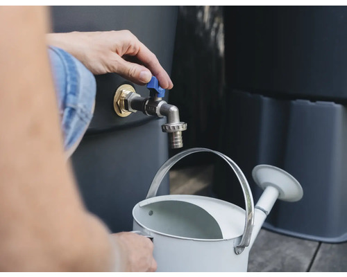 Persoon vult gieter met water uit regenton