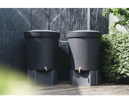 Twee donkere kunststof regentonnen met sokkel en kraan voor een donkere muur