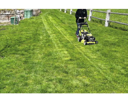 Een persoon maait gras met een grasmaaier in de tuin.