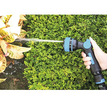 Hand houdt tuinslangspuitpistool vast bij het besproeien van planten