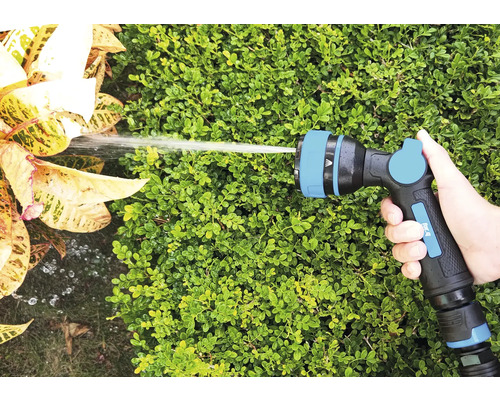Hand houdt tuinslangspuitpistool vast bij het besproeien van planten