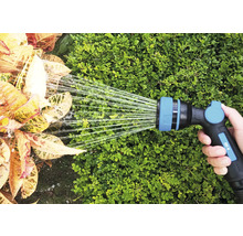 Een hand houdt een tuinslang vast die planten water geeft.