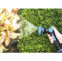 Een hand houdt een tuinspuit vast die water op planten spuit.