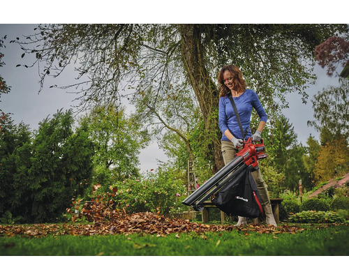Een vrouw gebruikt een bladblazer in de tuin om bladeren te verwijderen.