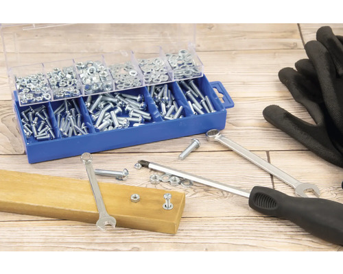 Assortimentsdoos met schroeven en moeren, moersleutels, schroevendraaier en handschoenen op een houten tafel