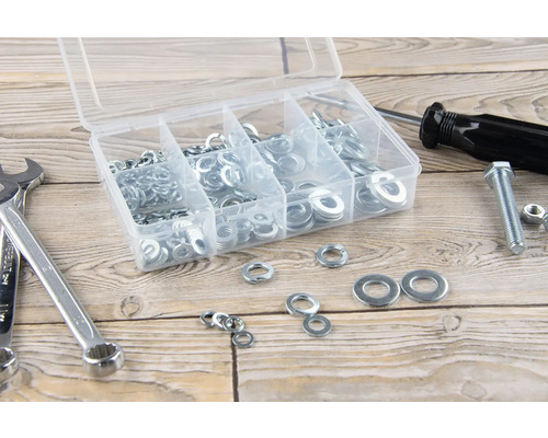 Assortimentsdoos met ringen, moersleutel, schroevendraaier, schroef en moer op een houten tafel