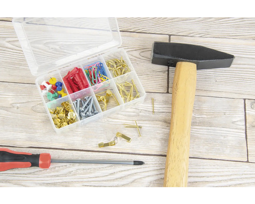 Hamer, schroevendraaier en sorteerdoos met schroeven, pluggen, spijkers, punaises en paperclips op een houten oppervlak