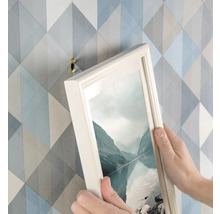 Persoon hangt foto met fotolijsthaak aan de muur