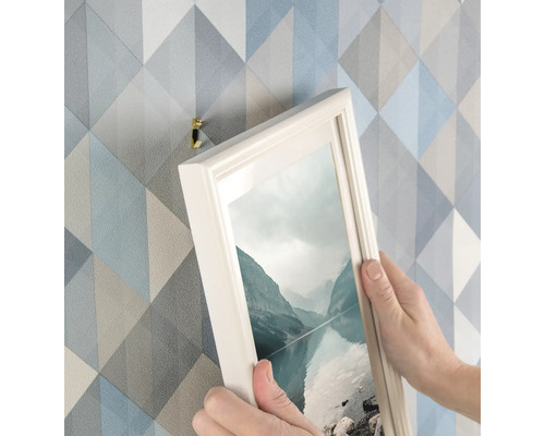 Persoon hangt foto met fotolijsthaak aan de muur