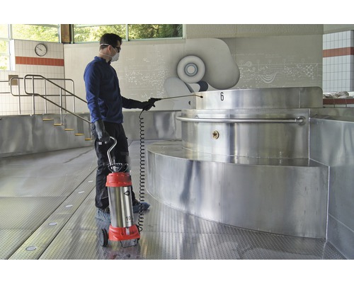 Man met beschermend masker en sproeier bij het desinfecteren van een zwembadinstallatie.