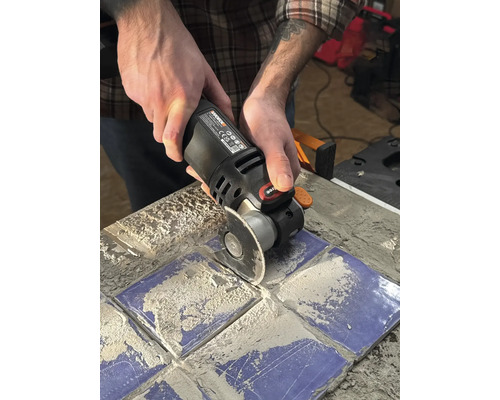 Iemand gebruikt een multifunctioneel gereedschap om tegels te snijden.