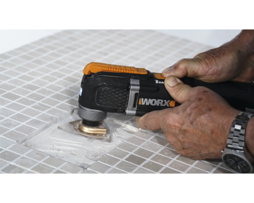 Gedetailleerd beeld van een persoon die tegels bewerkt met een multifunctioneel gereedschap, merk Worx
