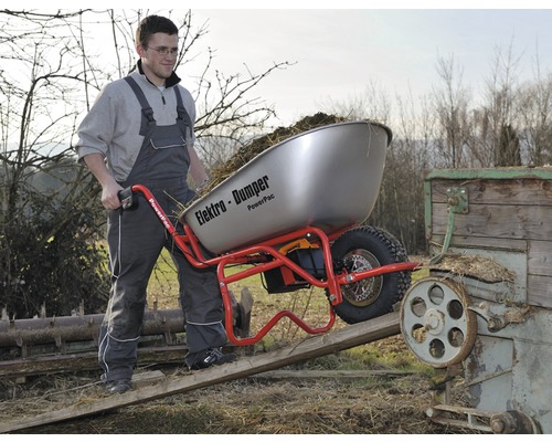 Man duwt een geladen elektrische kruiwagen met kantelfunctie over een helling