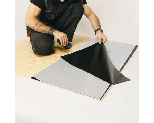 Ambachtsman brengt een afdichtingsbaan aan op een houten plaat