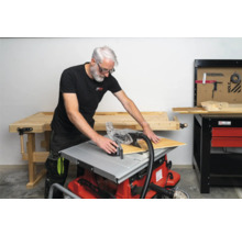 Man snijdt een houten plaat met een tafelcirkelzaag in een werkplaats.