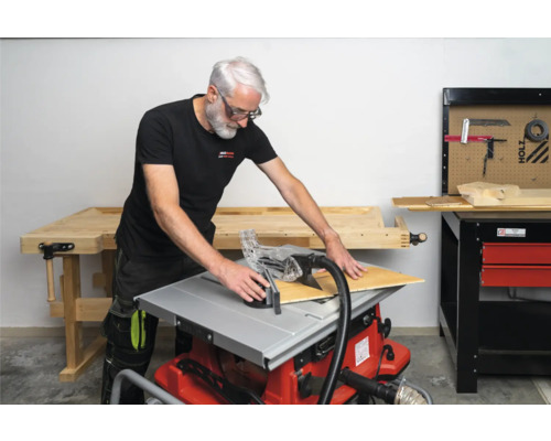 Man snijdt een houten plaat met een tafelcirkelzaag in een werkplaats.