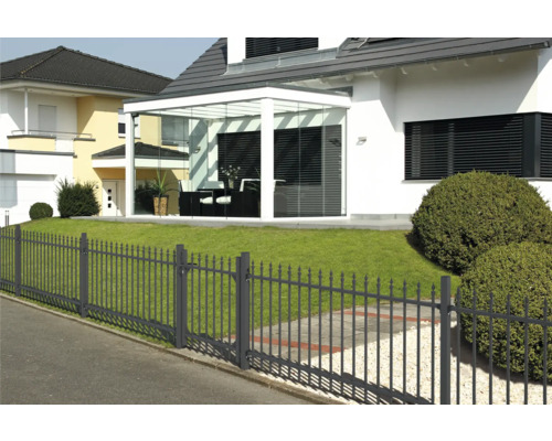 Huis met glazen aanbouw en metalen hek