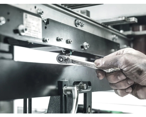 Een arbeider gebruikt een Wera Zyklop 8004 A ringsleutel om een schroef aan te draaien op een metalen constructie.