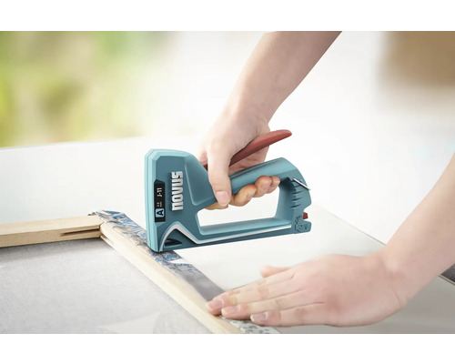 Een persoon gebruikt een Novus handtacker om een doek op een houten frame vast te nieten.