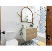 Badkamer met toilet, wastafelonderkast, spiegel en bad onder een douche met douchegordijn