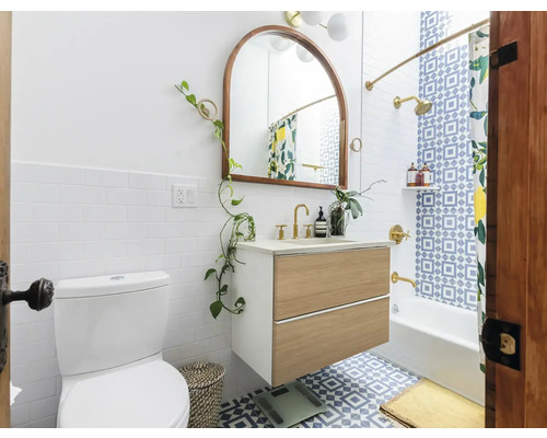 Badkamer met toilet, wastafelonderkast, spiegel en bad onder een douche met douchegordijn