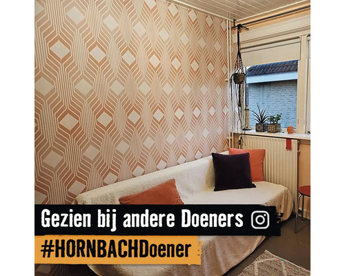 Woonkamer met bank en geometrisch behang.