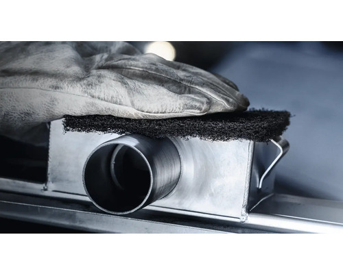 Metalen buis wordt bewerkt met een schuurvlies, beschermd door een werkhandschoen.