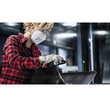 Een persoon met een beschermend masker, veiligheidsbril en handschoenen bewerkt een werkstuk.