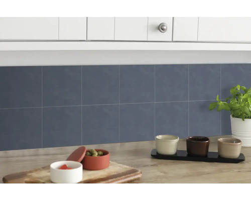 Keukenscène met blauwe wandtegels, aanrecht en keukengerei.