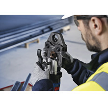 Een arbeider bedient een Bosch pijpkrimptang.