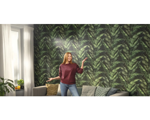 Woonkamer met groen bladbehang, bank en vrouw