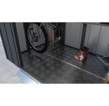 Interieur van een tuinhuis met fiets, tuingereedschap en laarzen op een traanplaatvloer