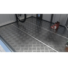 Metalen vloer met traanplaatpatroon, fiets en laarzen in de tuinschuur