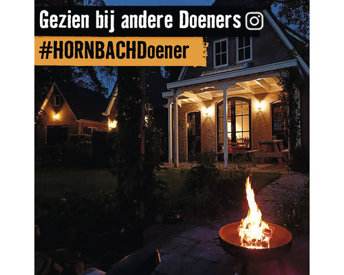 Avondtuinscene met vuurplaats en verlicht huis op de achtergrond