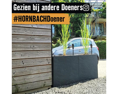 Grijze plantenbak met siergras en zonnelampen in de tuin