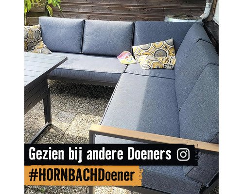 Grijze tuinlounge met tafel en kussens op een terras